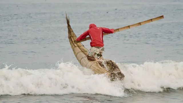 Hombre surfeando en un caballito de totora