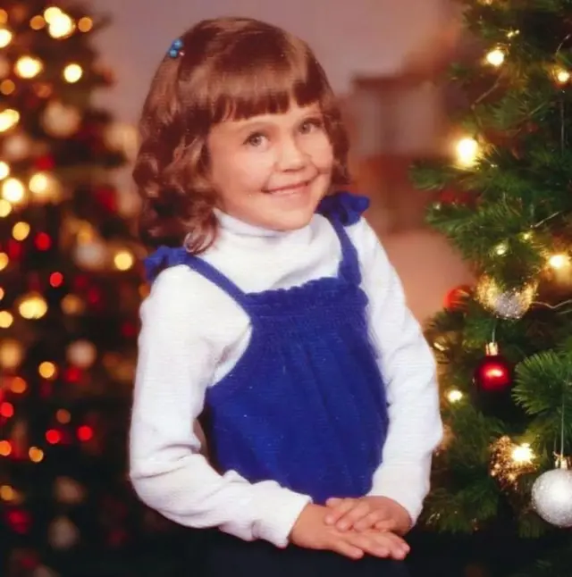 Alexis vestida de azul con árboles de Navidad