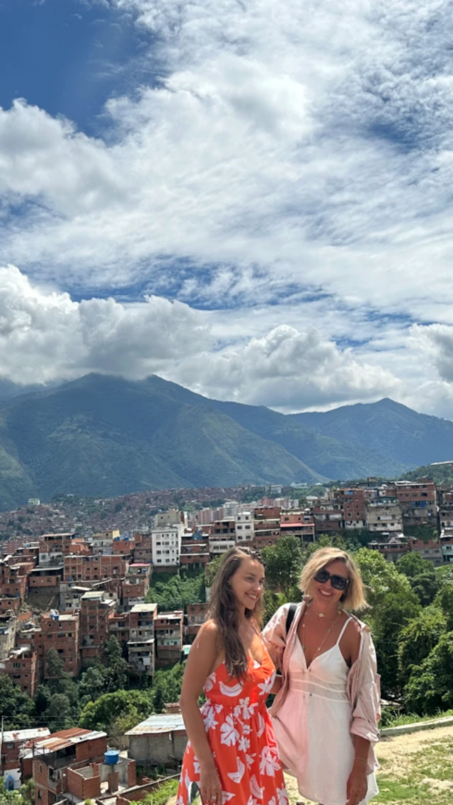 Dos turistas con el barrio de Petare al fondo.