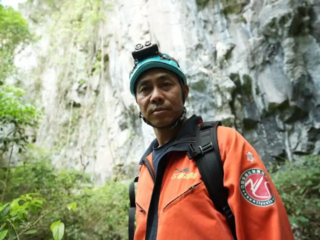 El Hermano Fei con un chaqueta naranja. 