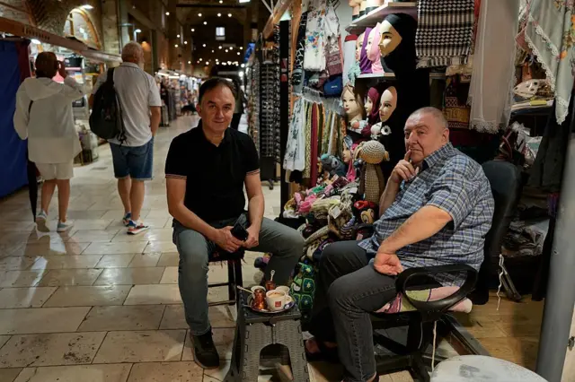 Dos hombres sentados en un bazar de Sarajevo.