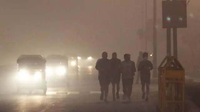 Personas trotando en Delhi en medio de una neblina gris