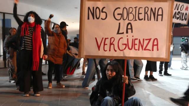 Un manifestante sostiene un cartel que dice