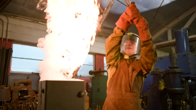 Ash en un taller mientras forja una espada durante un capítulo de la serie New Guy Tries