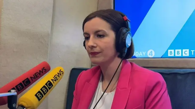MInistra con dos micrófonos de la BBC delante.