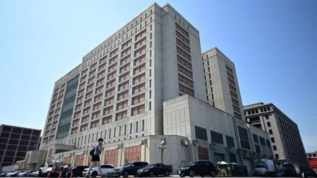 Una mujer con un teléfono móvil pasa por delante del Centro de Detención Metropolitano de Brooklyn, Nueva York.