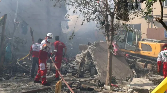 Socorristas iraníes trabajan alrededor de un edificio destruido por los ataques israelíes en Teherán, Irñan (13 de junio 2025)