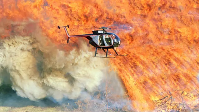 Un helicóptero sobrevuela un incendio forestal. 