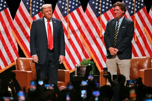 Donald Trump (izquierda) llega para una entrevista en directo con el comentarista estadounidense Tucker Carlson