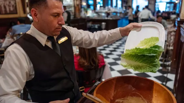 Mesero con un plato de lechugas