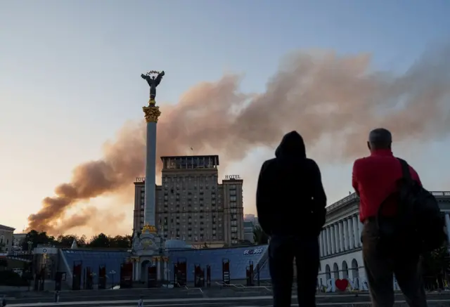 Unos hombres ven la columna de humo que sale del edificio del Gabinete.