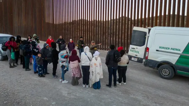 Inmigrantes esperan ser transportados por agentes de la Patrulla Fronteriza de EE. UU. después de cruzar la frontera entre EE. UU. y México el 20 de enero de 2025 cerca de Sásabe, Arizona. (Foto de John Moore/Getty Images)