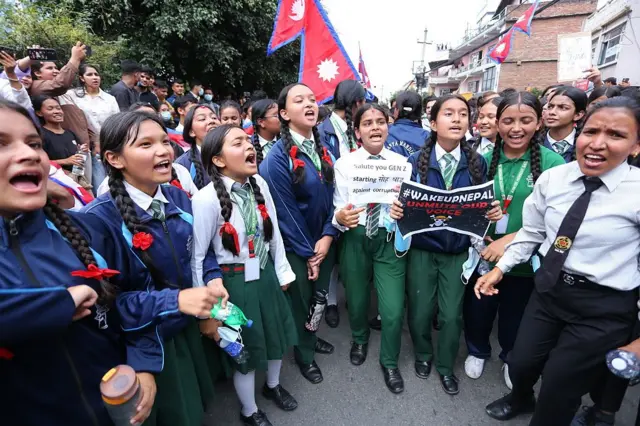 Niñas con uniforme escolar cantan afuera del parlamento en Katmandú, Nepal, el 8 de septiembre de 2025. Están reunidas en un arco, algunas sosteniendo carteles, mientras los adultos miran desde atrás.