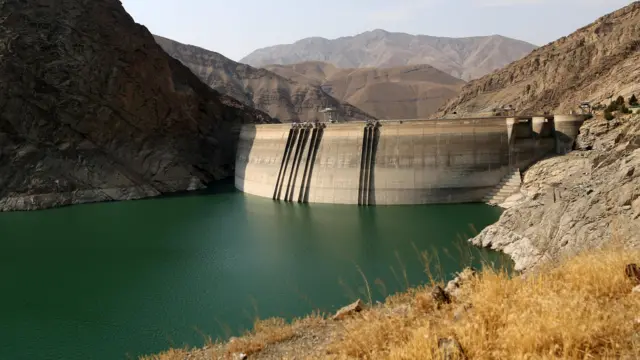 La presa de Amir Kabir con gran parte del muro de la presa expuesto el 29 de julio de 2025: escarpadas paredes rocosas de montaña rodean el agua.