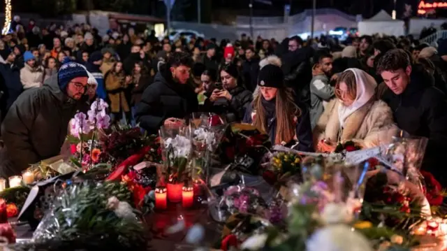 varias personas reunidas para una vigilia en homenaje a las víctimas del incendio 