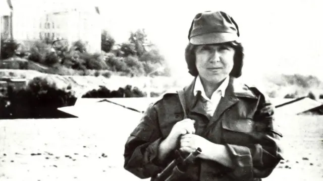 Svetlana Alexievich fotografiada en Kabul con ropa militar y una ametralladora sobre el hombro.