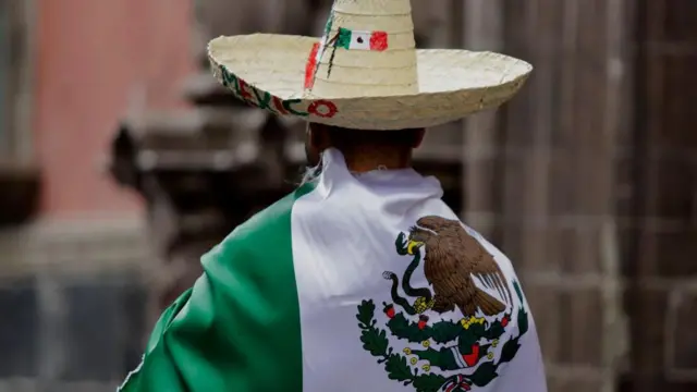 Un hombre cubre su cuerpo con una bandera de México.