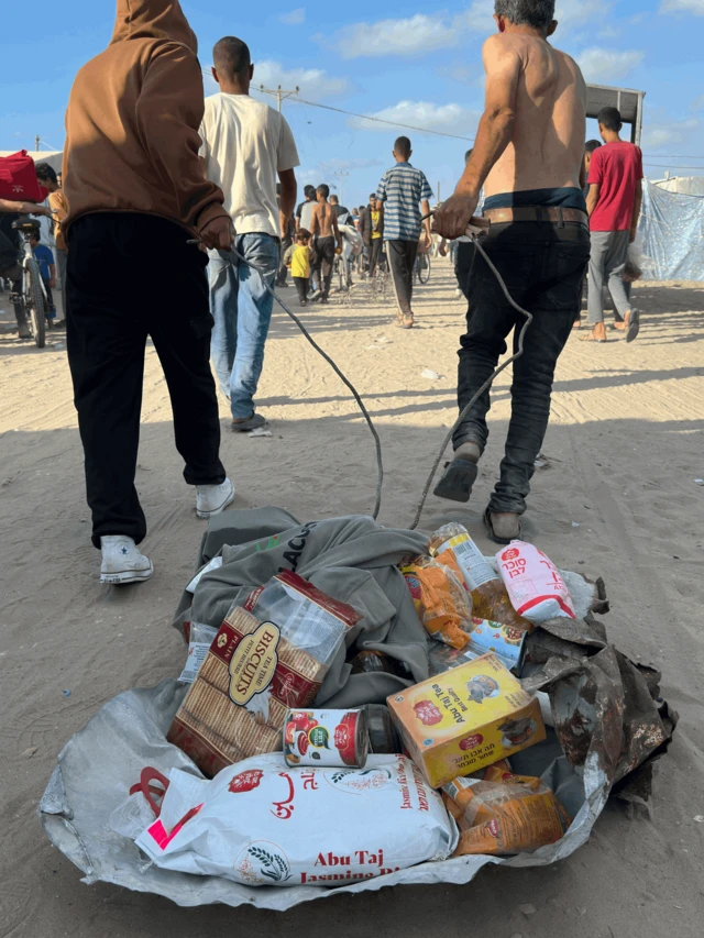 Dos hombres arrastran alimentos de una de las cajas de la FHG.