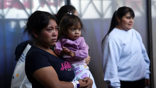 Una migrante guatemalteca sostiene a un niño tras llegar a la Base Aérea La Aurora en un vuelo de deportación desde Estados Unidos.