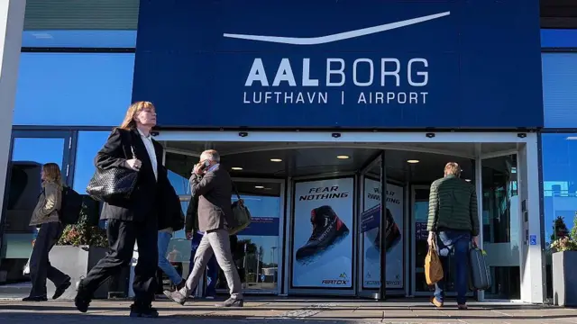 Pasajeros caminan frente a la terminal del aeropuerto de Aalborg.