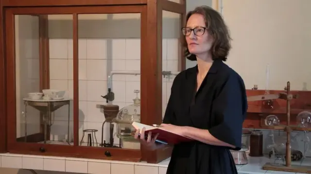 Sophie Hardock está parada en medio del laboratorio, con un cuaderno de gran tamaño en las tardes