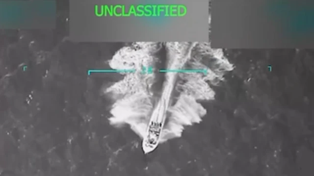 Un pequeño barco atraviesa el océano, en una imagen aérea en blanco y negro. 
