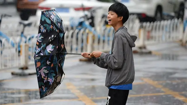 Un adolescente con paraguas camina por la calle bajo una intensa lluvia