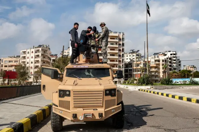 Fuerzas de seguridad leales al gobierno interino sirio colocan una torreta sobre un vehículo blindado estacionado en Latakia.