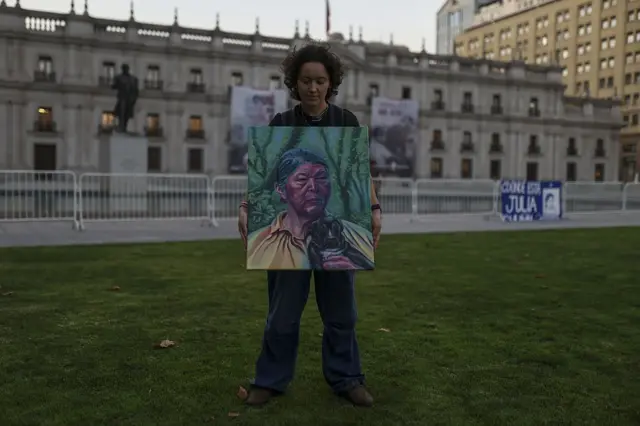 Una mujer posa con el retrato de Julia Chuñil al frente de la casa de gobierno en Santiago de Chile. 
