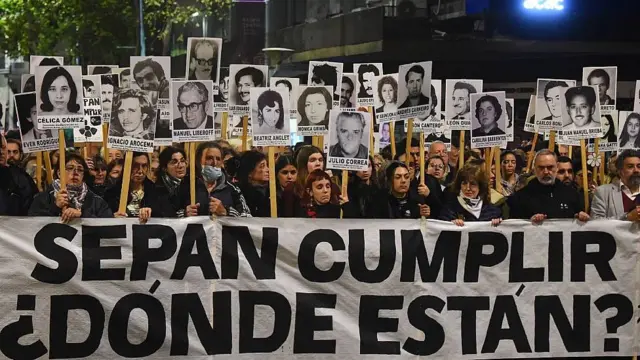 Cientos de personas marchan con carteles con imágenes de los desaparecidos en Uruguay. Al frente llevan una pancarta que dice 