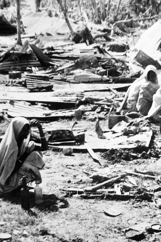 Una foto en blanco y negro muestra a personas damnificadas por la destrucción de un ciclón.