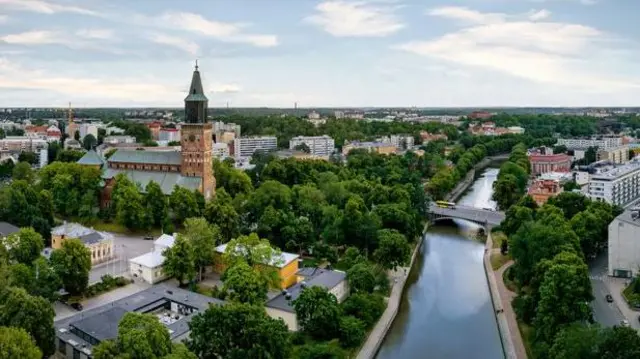 Vista aérea del río Aura y la catedral de Turku, entre árboles y edificios.