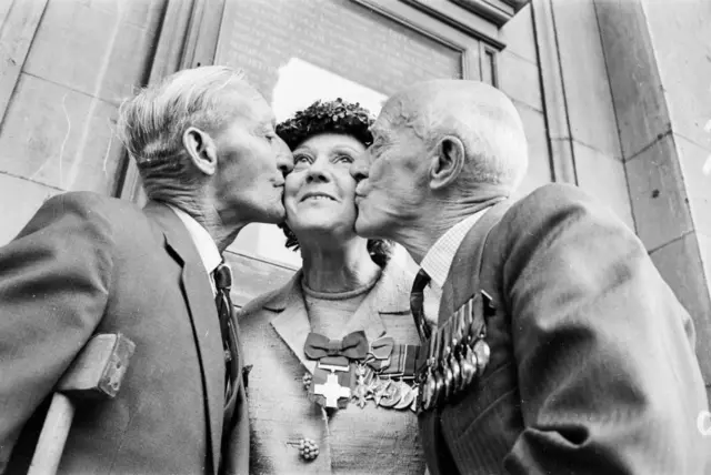 El sargento R. Ryder y el teniente coronel T. E. Adlam le dan un beso en cada mejilla a Odette en una convención de héroes de guerra condecorados con la Medalla George o la Cruz Victoria.