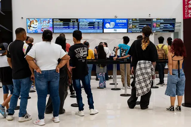 Un grupo de personas, vistas de espaldas, hacen fila en un centro de ocio de Bogotá. 