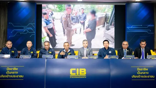 Agentes de policía sentados detrás de una mesa larga.