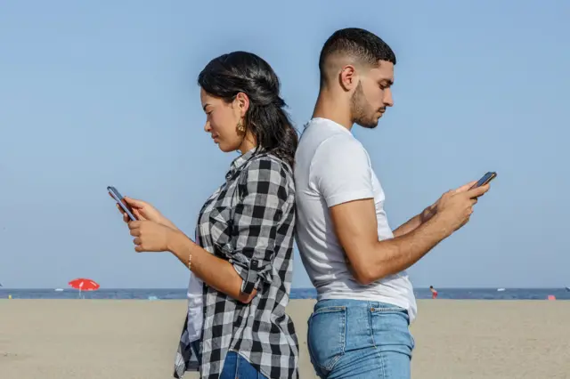 Un hombre y una mujer con sus teléfonos móviles.