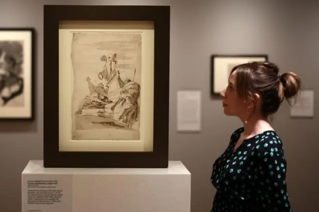 Una asistente de galería examina la obra