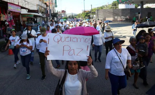 Varias personas vestidas de blanco en una manifestación en México por la paz. Una mujer lleva una pancarta en la que puede leerse: