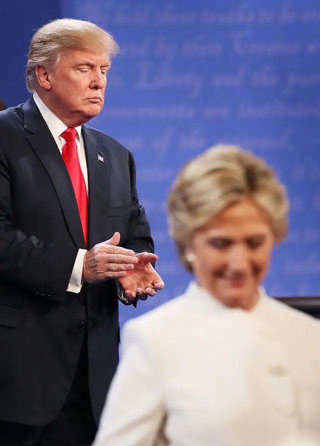 Hillary Clinton deja el escenario mientras Donald Trump aplaude durante un debate 