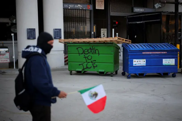 Persona con la bandera de México y un cartel que dice