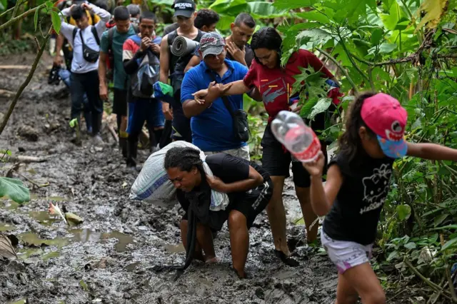 Un grupo de migrantes camina por un estrecho fangoso en el Darién