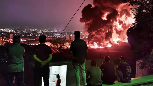 Varias personas observan el fuego y el humo provocados por un ataque israelí contra el depósito de petróleo de Shahran, en Teherán, el 15 de junio de 2025