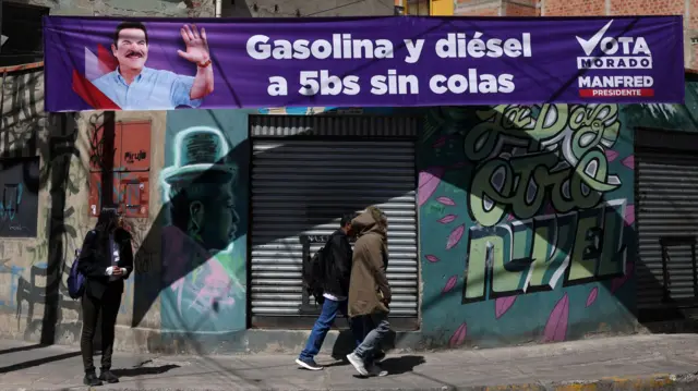 La gente pasa junto a una pancarta del candidato presidencial boliviano Manfred Reyes Villa, del partido 