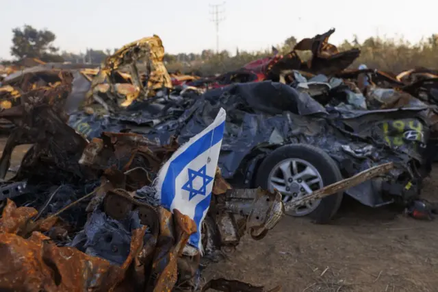 Una bandera israelí entre los vehículos destruidos en el ataque del 7 de octubre por militantes de Hamás.