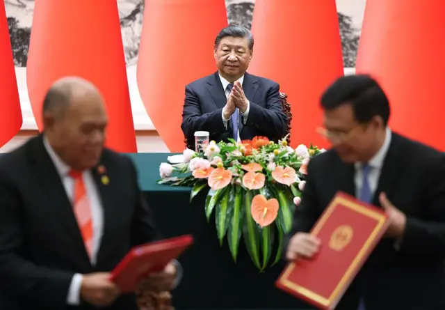 Xi Jinping aplaude mientras uno de sus ministros firma un acuerdo con un delegado europeo.
