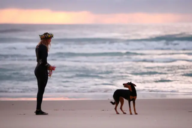 Ellidy Pullin con su perro al atardecer, frente al océano