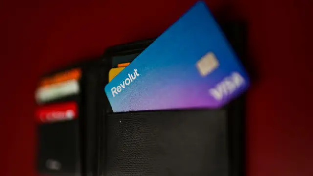 Una cartera llena de tarjetas de pago en la que destaca la morada de Revolut.