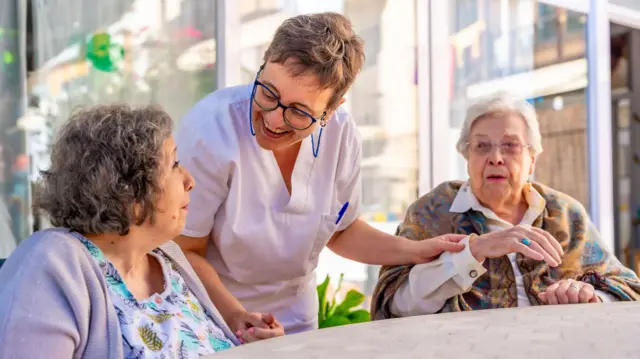 Dos personas de la tercera edad son asistidas por una enfermera
