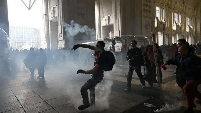 Un manifestamte lanza algo en medio de enfrentamientos con la policía antidisturbios en la estación de tren Milano Centrale, en Milán, el 22 de septiembre de 2025.