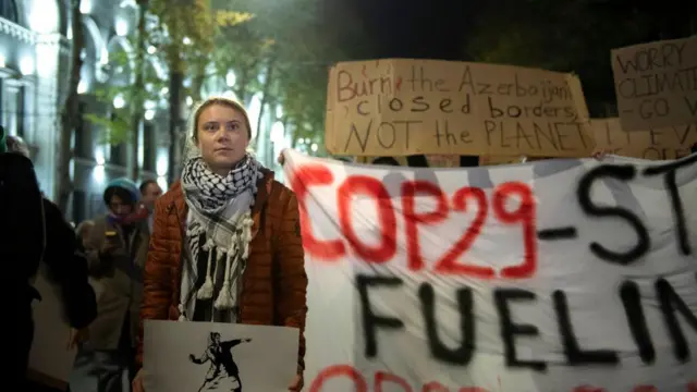 Greta Thunberg en una protesta en Georgia junto a una pancarta que dice 